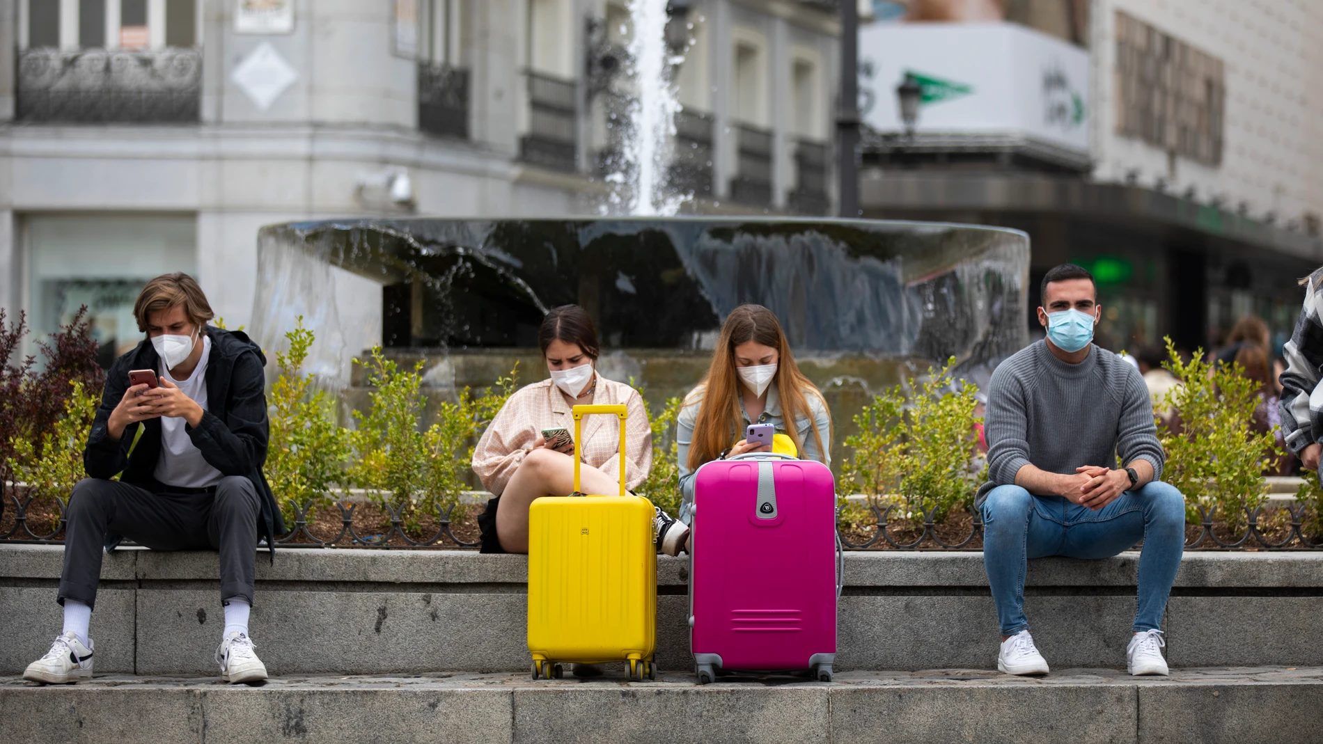 Imagen de dos chicas con dos coloridas maletas en la Puerta del Sol.