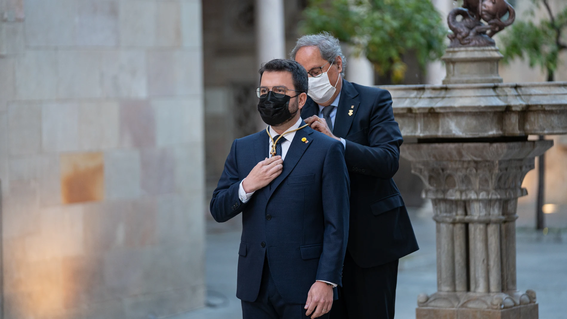 El expresidente de la Generalitat, Quim Torra (d), impone la medalla de presidente de la Generalitat de Catalunya a Pere Aragonès (i) en el Pati dels Tarongers del Palau de la Generalita.