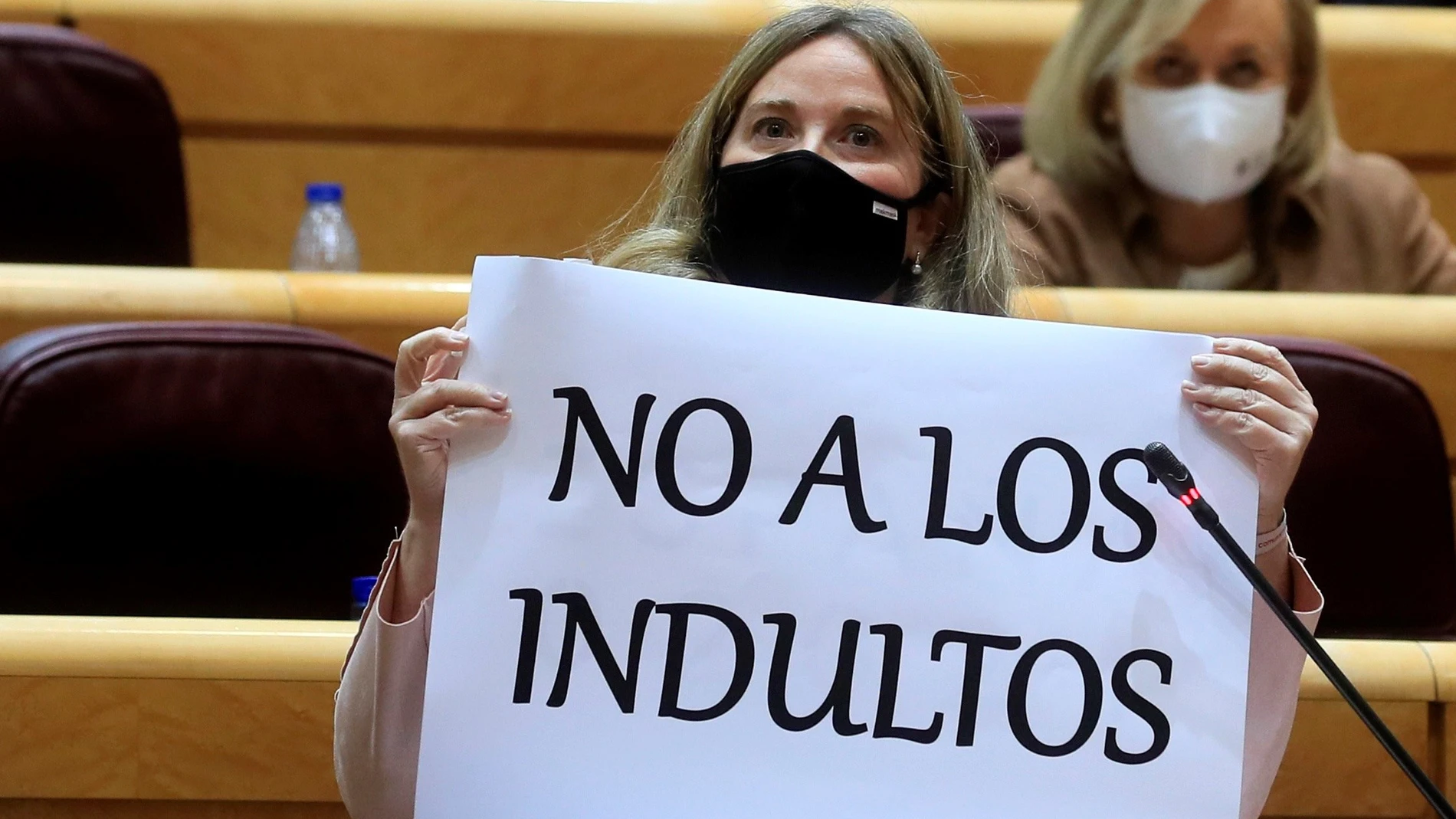 La senadora del PP, Cristina Ayala Santamaría, muestra un cartel en relación a su pregunta al ministro de Justicia, Juan Carlos Campo