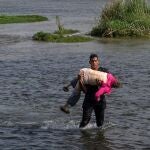 Un solicitante de asilo de Venezuela lleva a una anciana mientras camina en el agua para cruzar el río Grande hacia Estados Unidos desde México