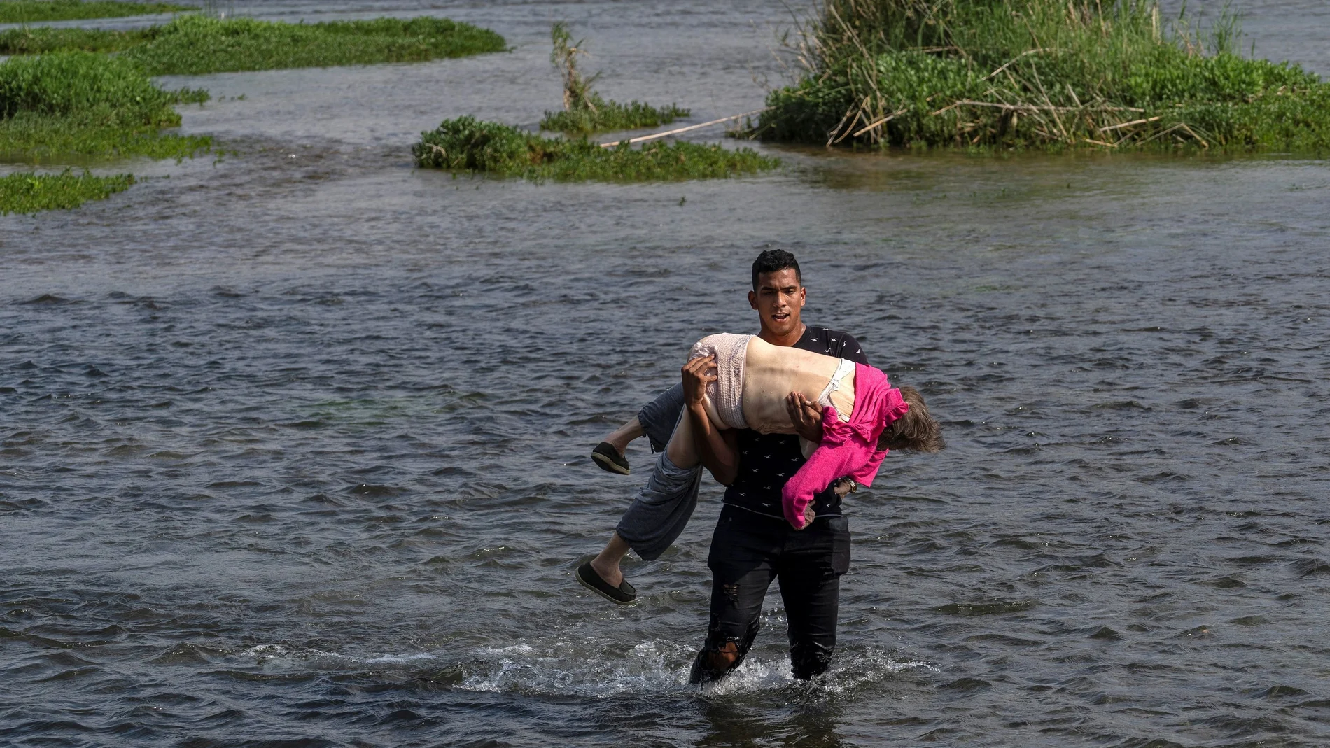 Un solicitante de asilo de Venezuela lleva a una anciana mientras camina en el agua para cruzar el río Grande hacia Estados Unidos desde México