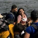 Una mujer migrante solicitante de asilo de Venezuela reacciona mientras camina en el agua para cruzar el río Grande hacia Estados Unidos desde México en Del Río, Texas