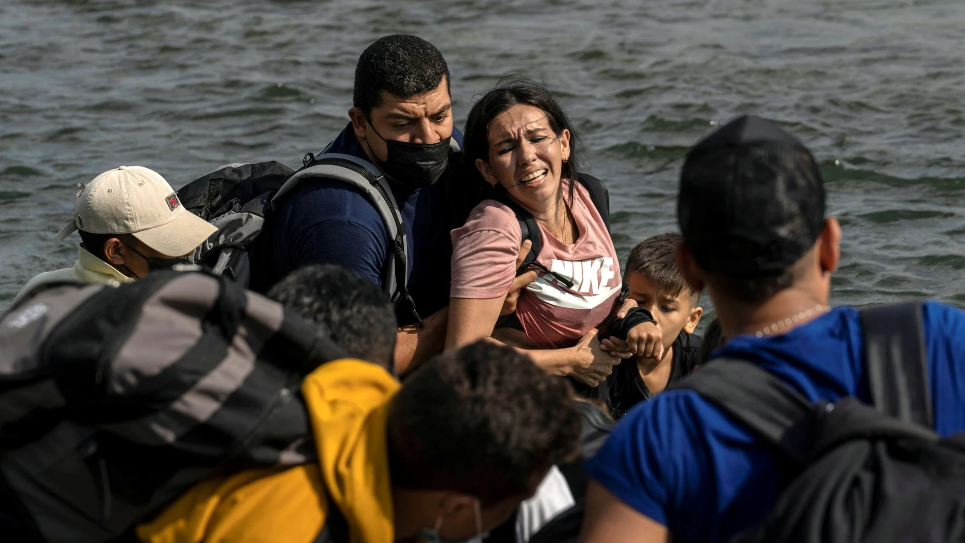 Una mujer migrante solicitante de asilo de Venezuela reacciona mientras camina en el agua para cruzar el río Grande hacia Estados Unidos desde México en Del Río, Texas