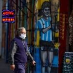 A man wearing a face mask as a preventive measure against the coronavirus disease (COVID-19) walks past a grocery store painted with a graffiti depicting Diego Maradona, after CONMEBOL announced Argentina pulled out hosting the Copa America, in Buenos Aires, Argentina May 31, 2021. REUTERS/Agustin Marcarian