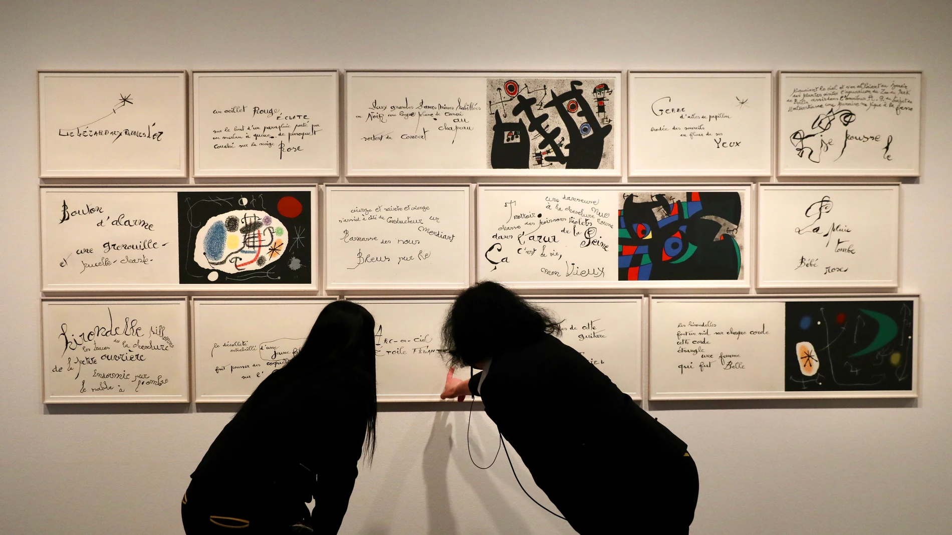 Dos visitantes contemplan un poema de Miró ilustrado por sí mismo