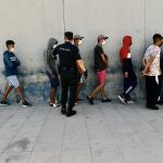 Varios inmigrantes procedentes de Marruecos hacen cola en las puertas de la frontera de Ceuta