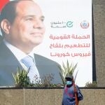 Un barrendero municipal frente a un cartel propagandístico del presidente Abdel Fatah Al-Sisi en El Cairo
