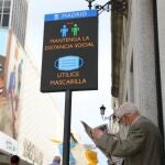Un jubilado lee el periódico en una calle comercial madrileña