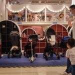 Un padre y su hijo pasan junto a una tienda de bebés en un centro comercial de Pekín
