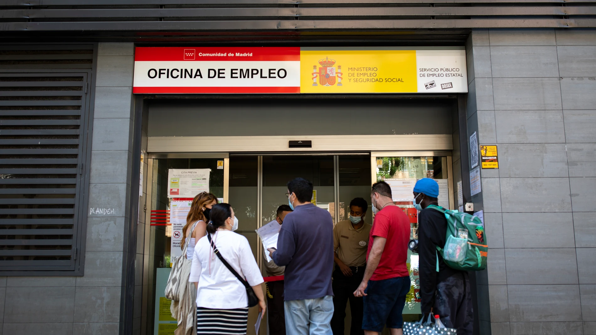 Varias personas esperan a la puerta de una oficina de empleo de Madrid