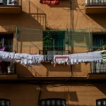 Imagen de una mujer tendiendo la ropa de la lavadora en el balcon de su casa en un edificio de Vallecas.