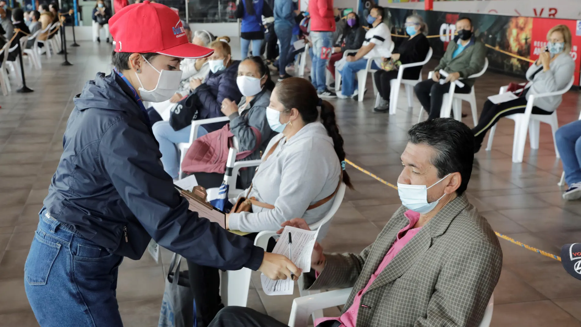 Personal de asistencia registra a un grupo de personas que recibirá la vacuna contra la covid-19 hoy, en el Mallplaza, uno de los centros comerciales habilitados como punto de vacunación masiva, en Bogotá (Colombia)