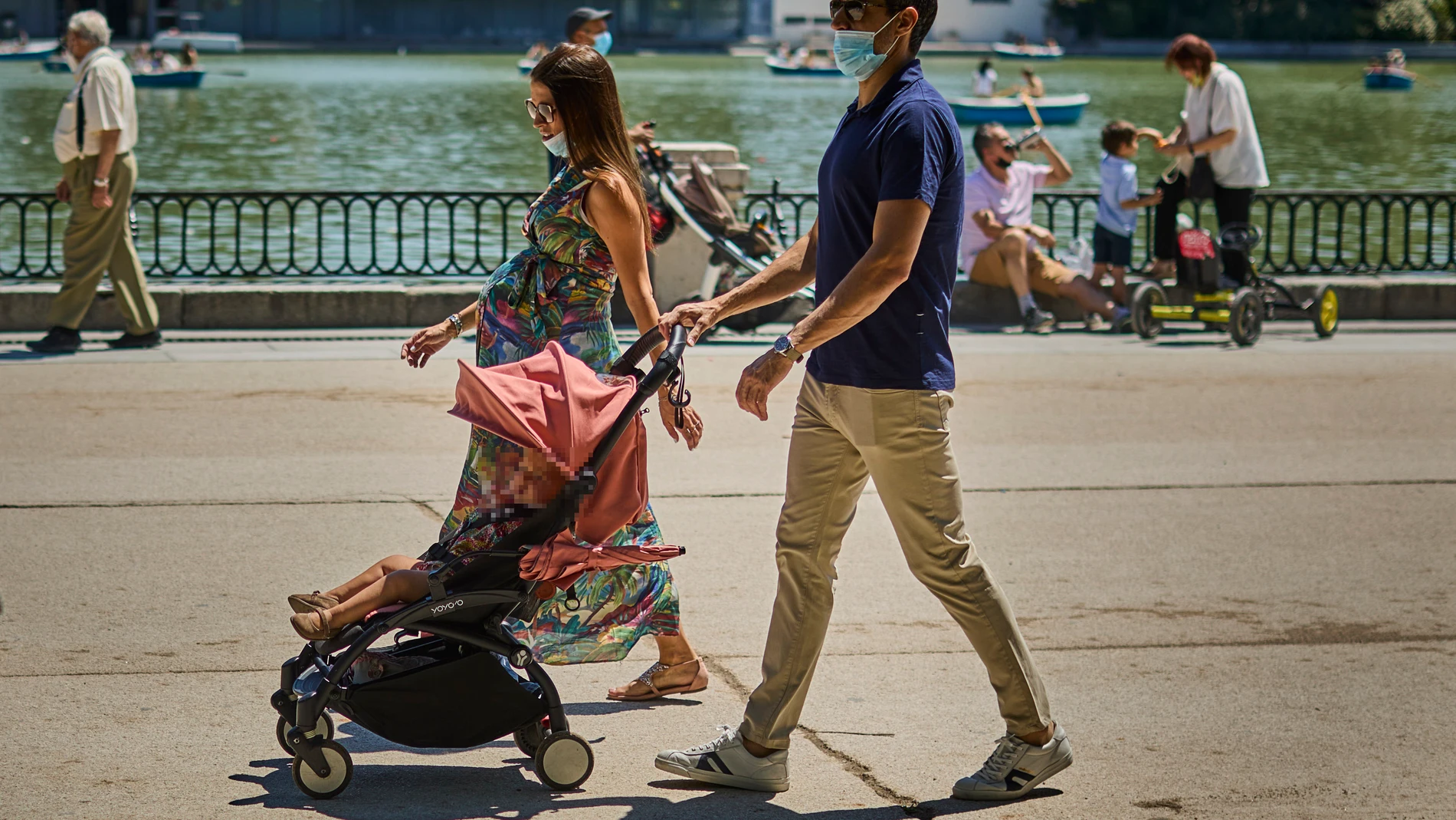 Familias con sus carritos de bebe pasean por el Retiro madrileño.