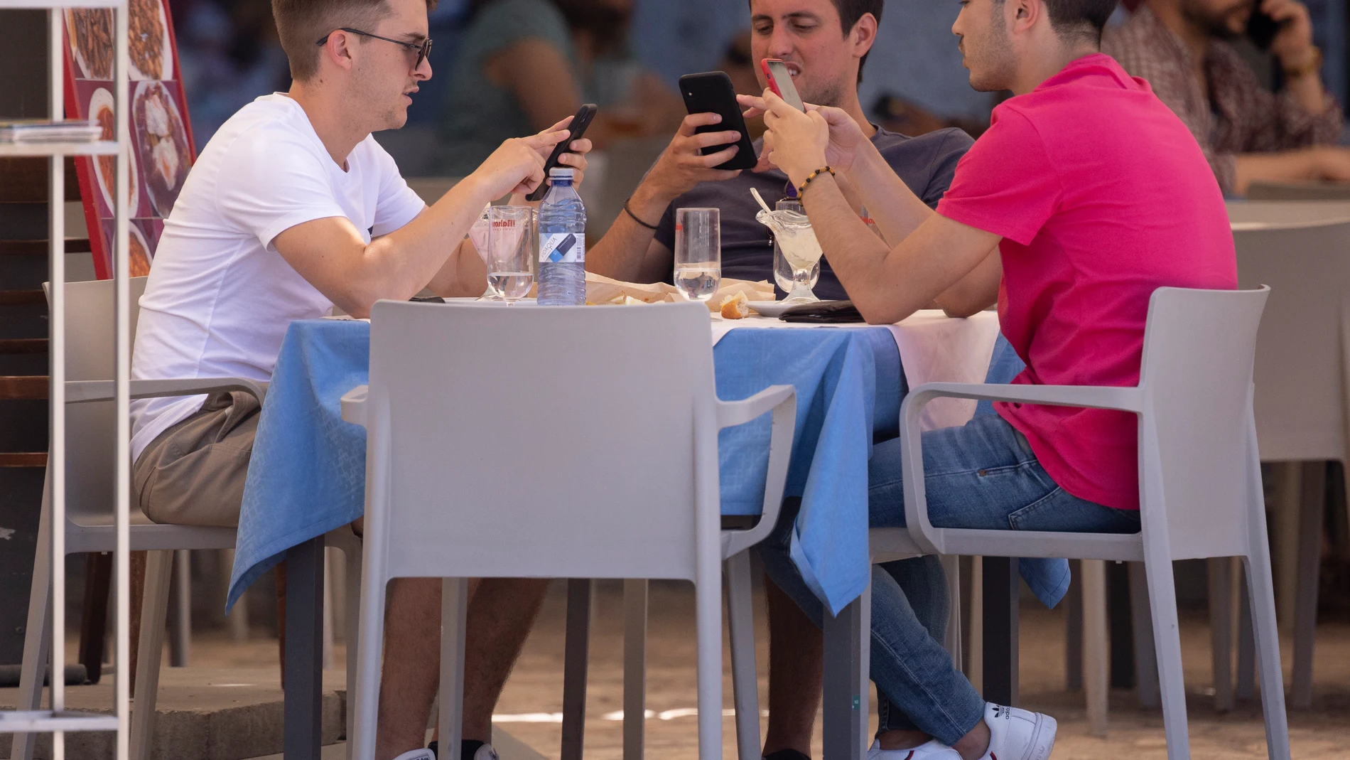 Tres hombres comen en una terraza del centro de la capital