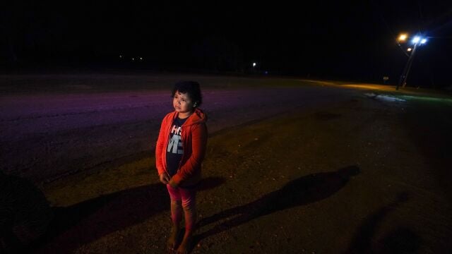 FILE - In this May 13, 2021, file photo, Emely, 8, of Honduras, stands alone after turning herself in upon crossing the U.S.-Mexico border in La Joya, Texas. Her mother, Glenda Valdez was at her home in Austin, watching a Univision newscast one afternoon in May, when she saw this picture of Emely in a red hoodie. She knew at once that it was her daughter. Desperate, she immediately began making calls to U.S. authorities, the network and refugee agencies. (AP Photo/Gregory Bull, File)
