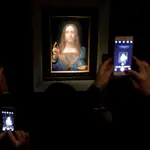 Varias personas fotografían la obra &#39;Salvator Mundi&#39; del artista Leonardo da Vinci (1500), durante una vista previa pública antes de que la casa Christie&#39;s lo subastara