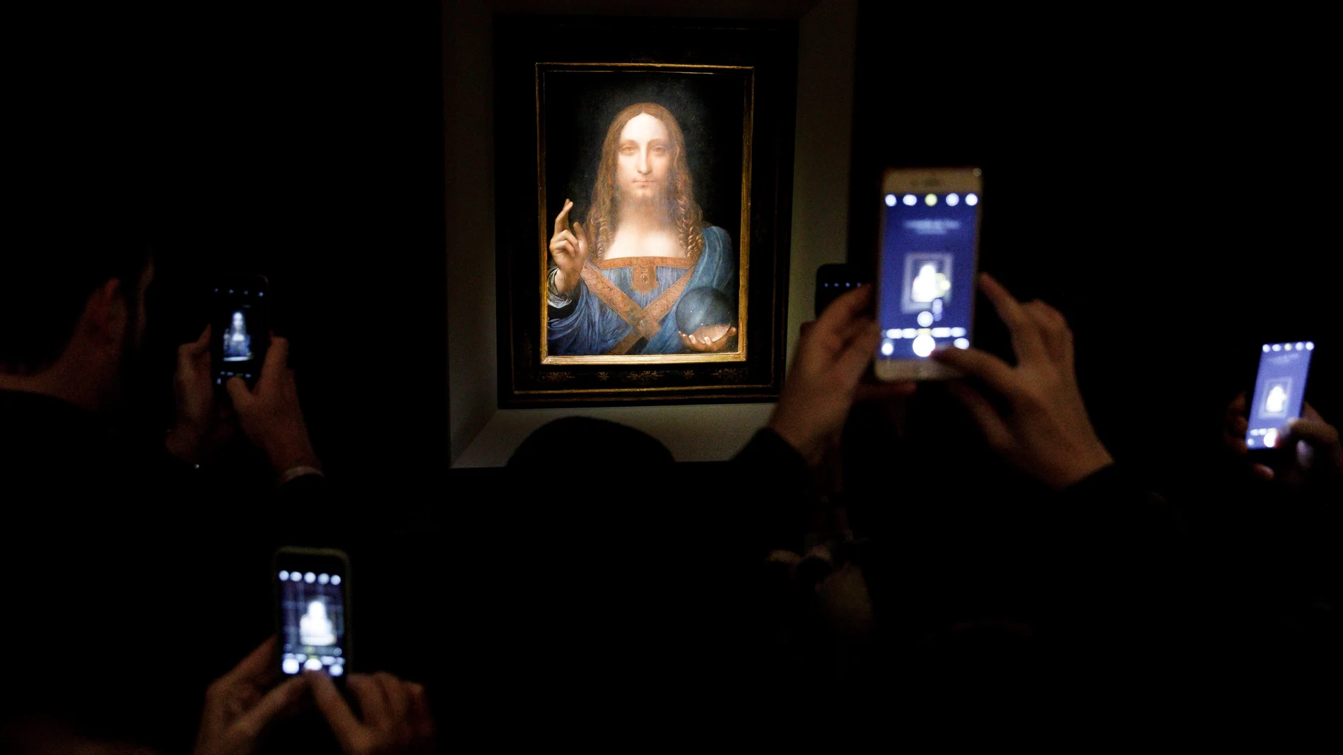 Varias personas fotografían la obra 'Salvator Mundi' del artista Leonardo da Vinci (1500), durante una vista previa pública antes de que la casa Christie's lo subastara