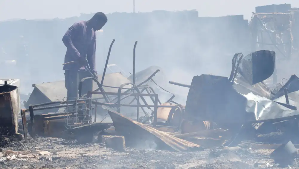 Un hombre busca entre los enseres quemados en el incendio declarado em junio en un asentamiento de chabolas ubicado en el término municipal de Níjar (Almería)
