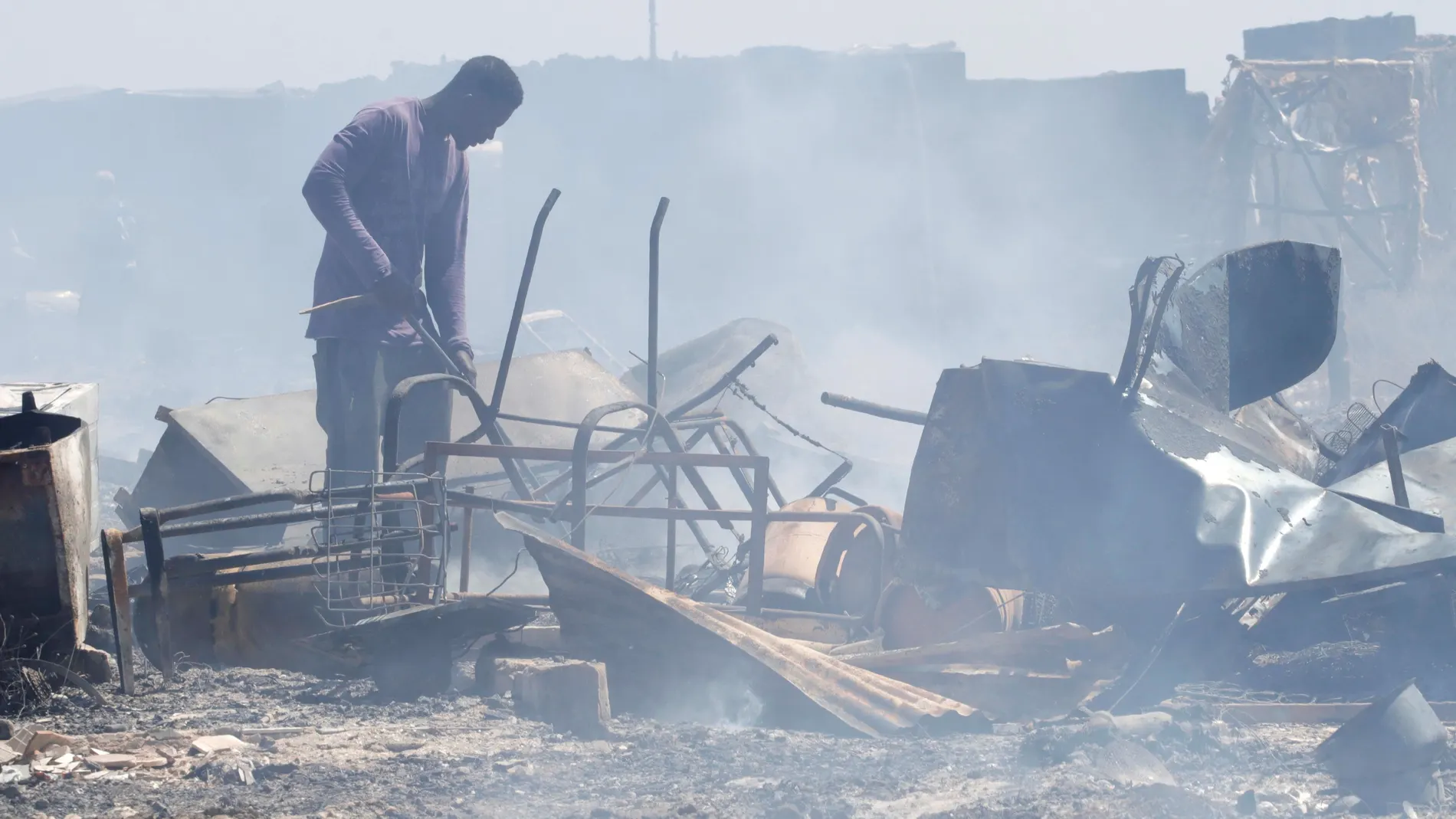 Un hombre busca entre los enseres quemados en el incendio declarado em junio en un asentamiento de chabolas ubicado en el término municipal de Níjar (Almería)