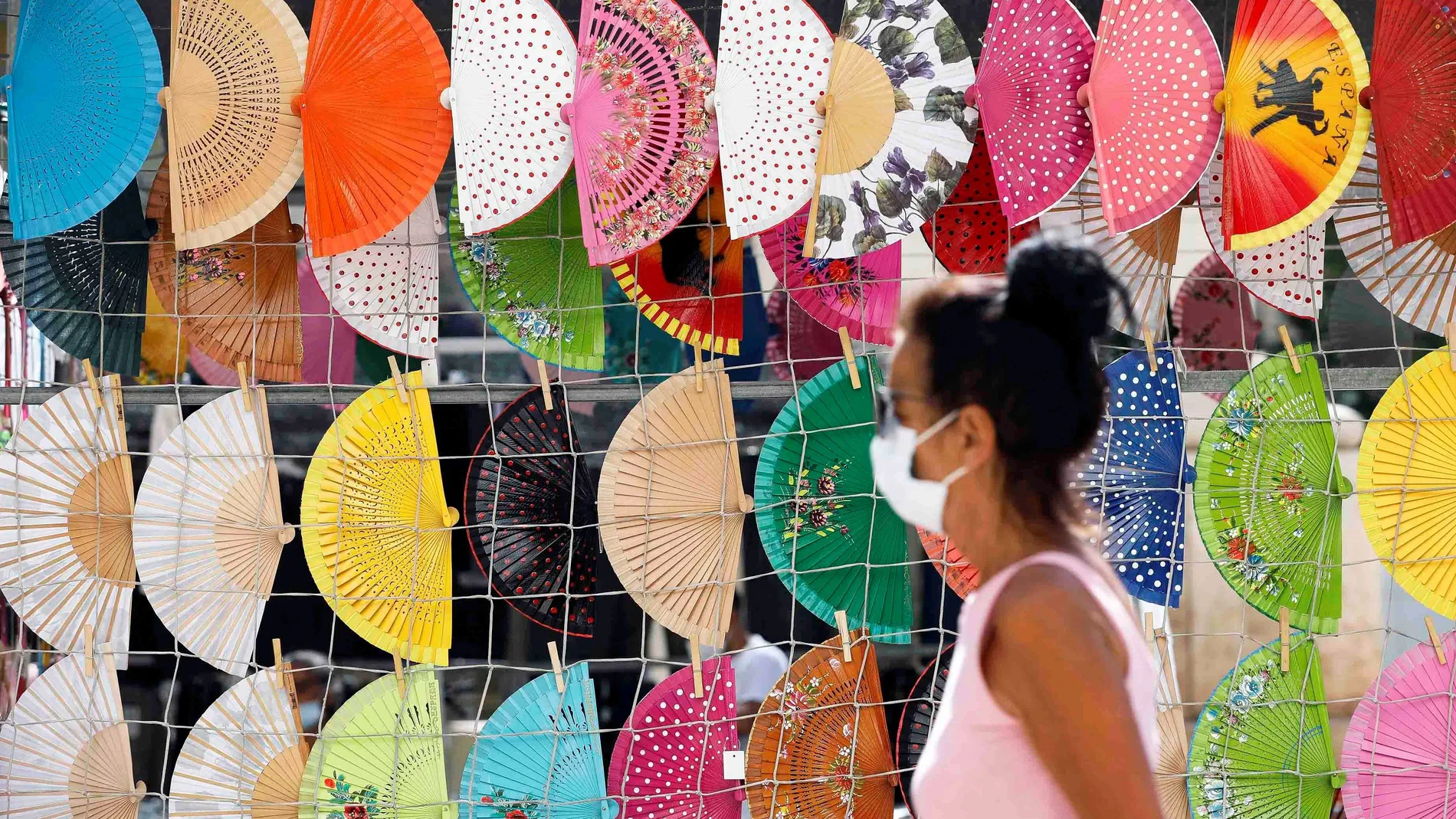Una persona pasa frente a un puesto del centro de Valencia donde se venden abanicos, este lunes 21 de junio, día en el que da comienzo el verano