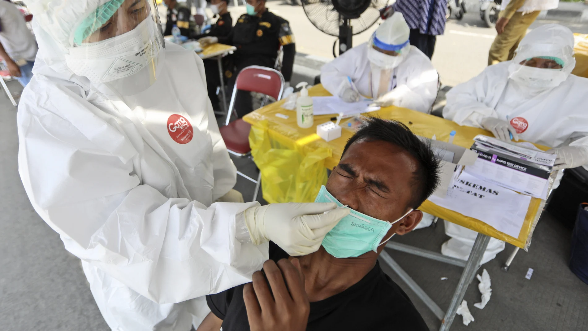 Un sanitario toma una muestra de hisopo nasal de un hombre durante una prueba de coronavirus obligatoria para quienes viajan entre la isla de Madura y la capital provincial de Surabaya (Indonesia)