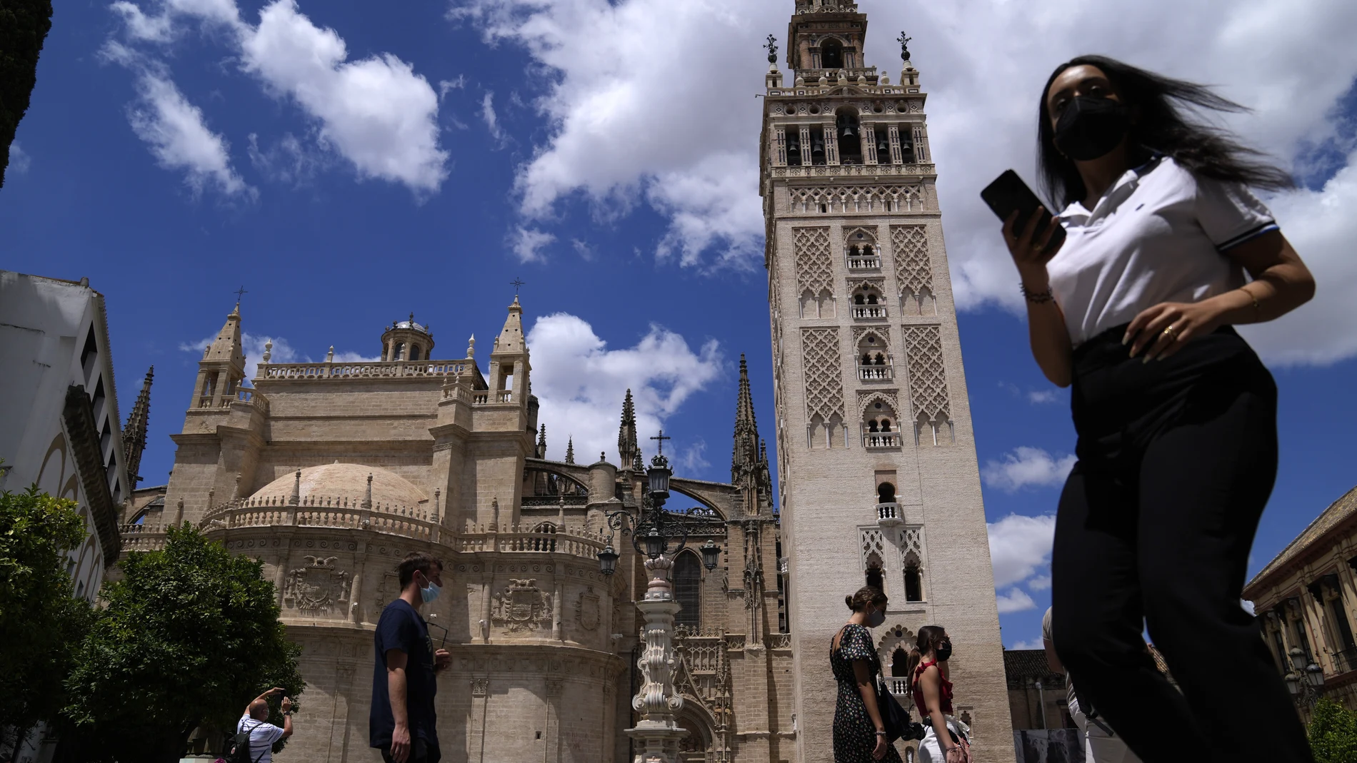 Varias personas pasean por el centro de Sevilla con mascarilla
