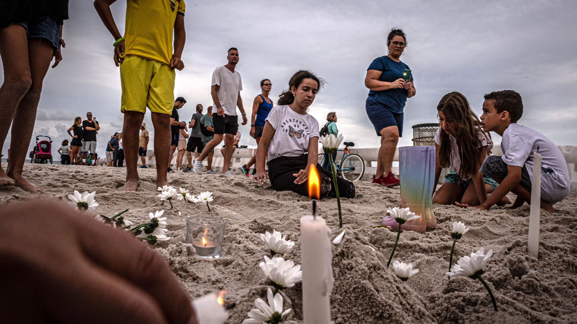 Unos niños encienden velas durante una pequeña vigilia en memoria de los desaparecidos en el derrumbe del edificio de Surfside, Florida. EFE