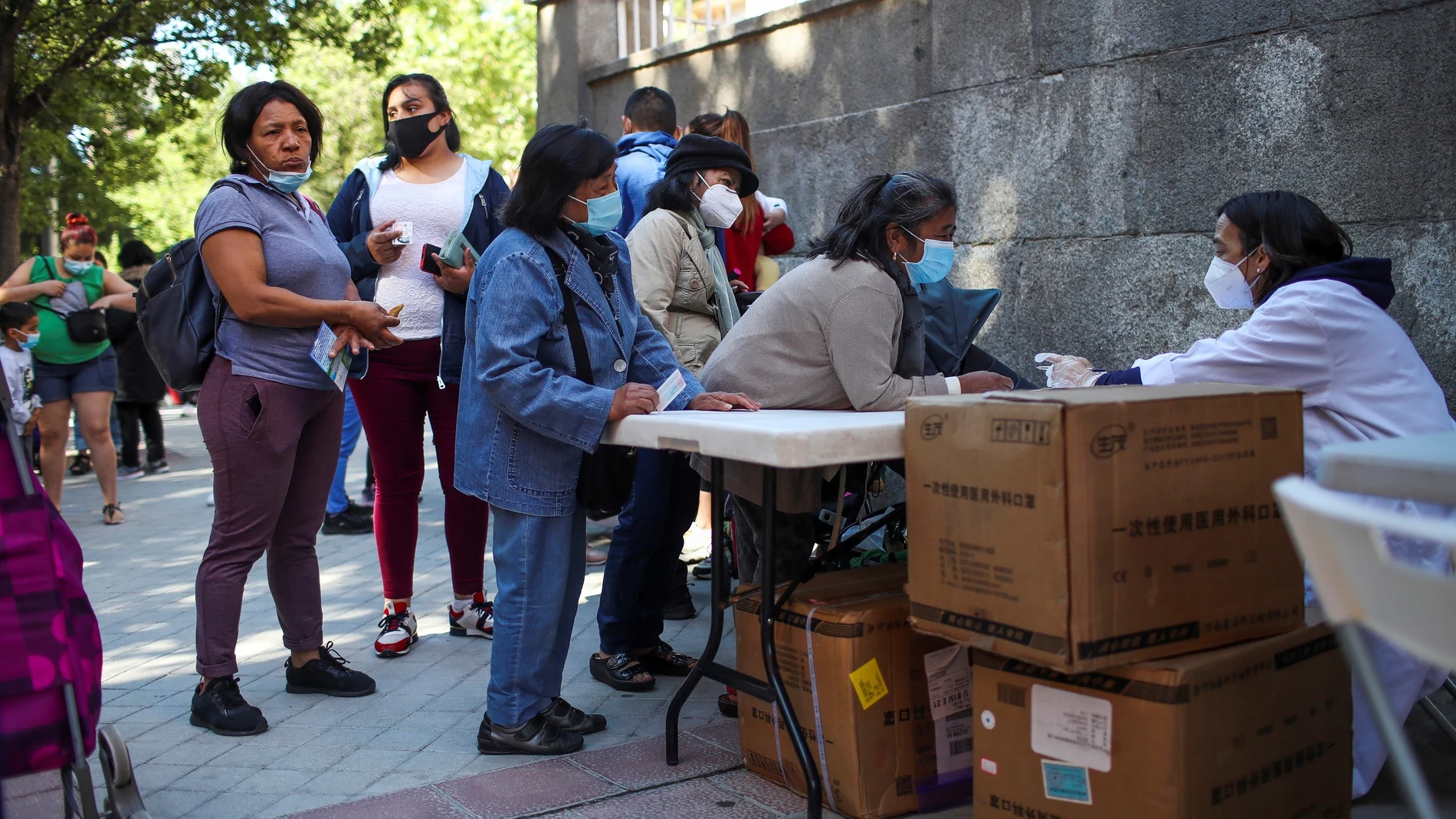 Decenas de personas acuden al reparto de alimentos que la Fundación Madrina realiza en la Plaza San Amaro en Madrid el pasado junio