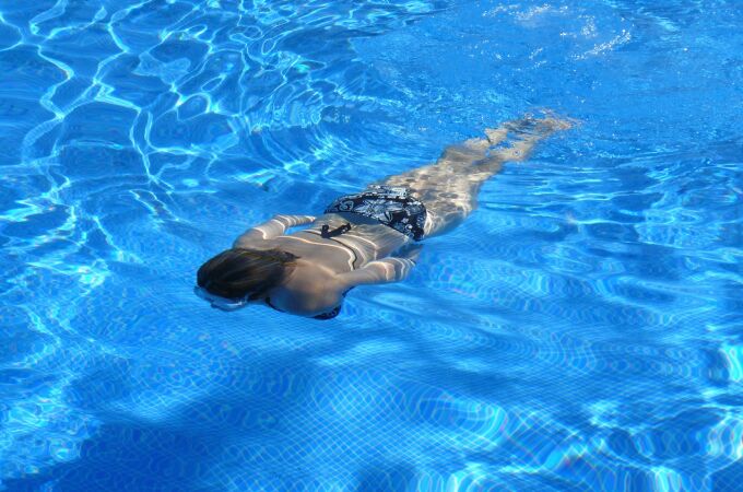 Una mujer bucea en una piscina con el agua cristalina