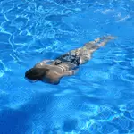 Una mujer bucea en una piscina con el agua cristalina