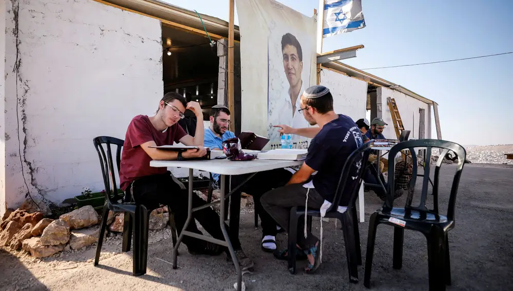 Colonos judios estudian juntos en una mesa en Eviatar