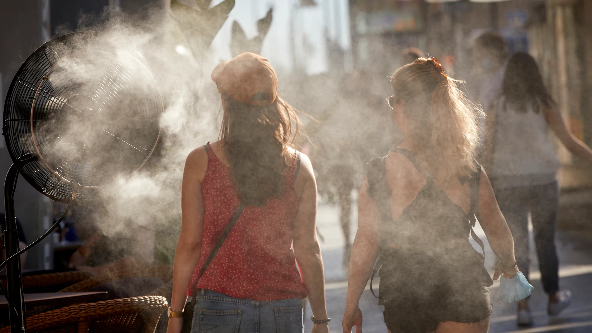 Varias personas caminan al lado de un difusor de vapor de agua de un restaurante de la calle Alcalá.