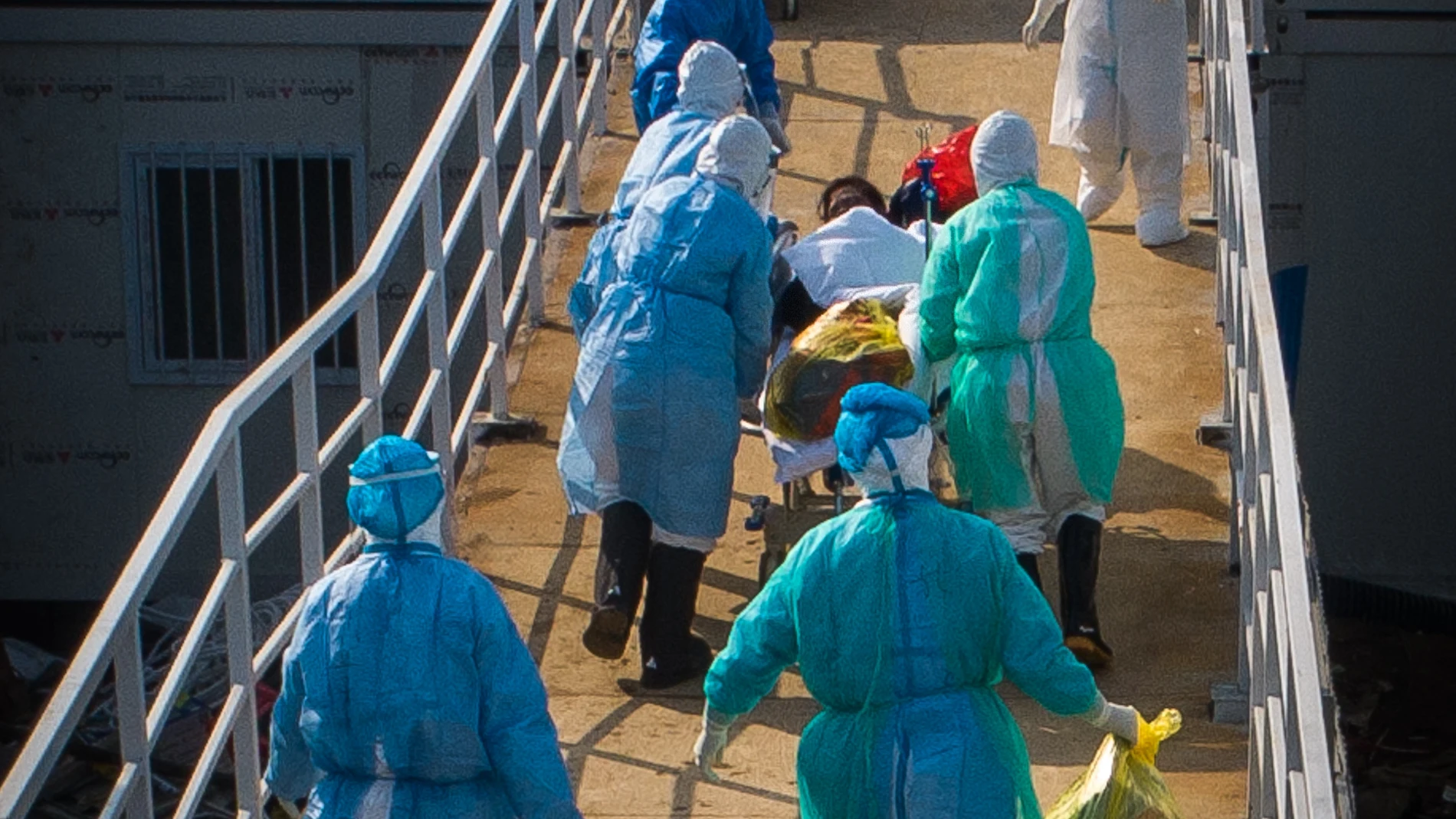 Esta imagen, captada el 4 de febrero de 2020, muestra personal médicoayudando a un paciente con COVID-19 a trasladarse a las salas deaislamiento del Hospital Huoshenshan (Montaña del Dios del Fuego), en Wuhan, capital de la provincia central china de Hubei