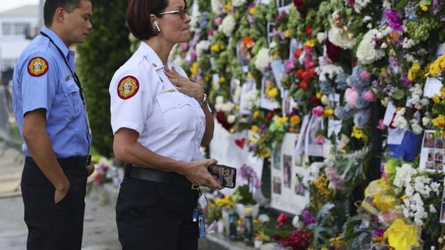 From left, Miami-Dade Fire Rescue personnel Fai Yeung and Chief Melanie C. Adams visit the makeshift memorial setup near the partially collapsed 12-story Champlain Towers South Condo in Surfside, Fla., Thursday, July 1, 2021. Search is paused because of structural concerns officials say. The apartment building partially collapsed on Thursday, June 24. (David Santiago /Miami Herald via AP)