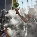 Un chico se refresca del calor con un difusor de vapor de agua de un restaurante de la calle Alcalá