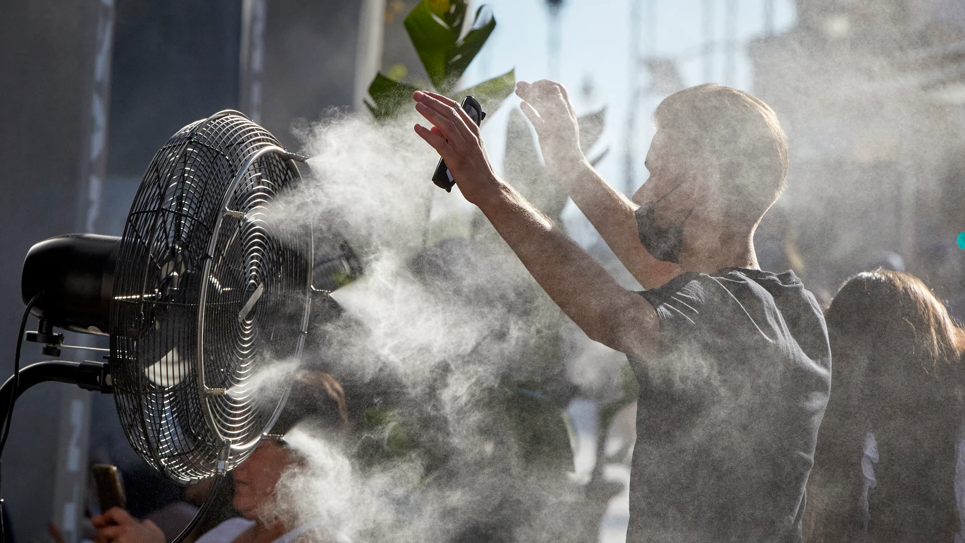 Un chico se refresca del calor con un difusor de vapor de agua de un restaurante de la calle Alcalá