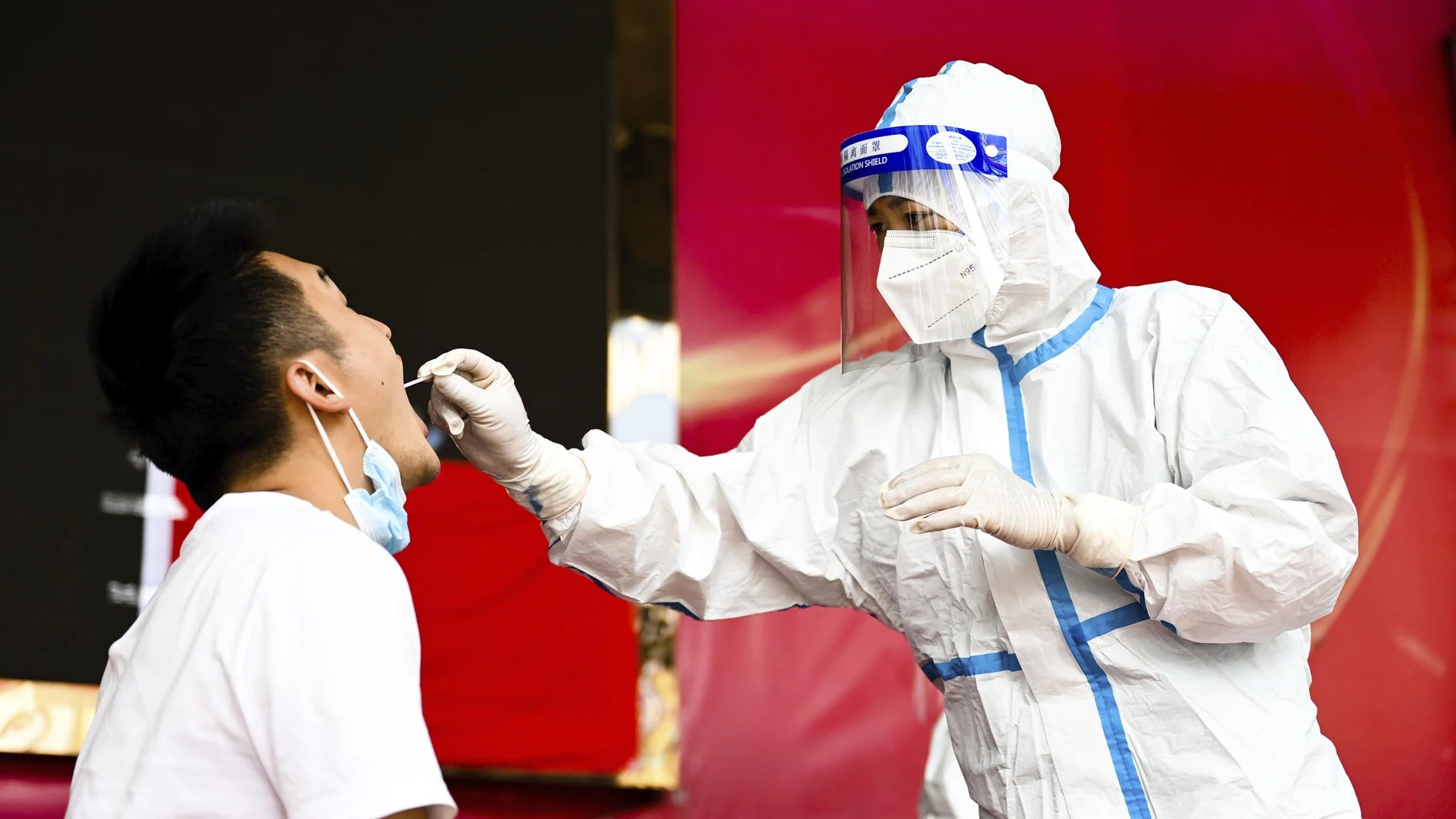 In this photo released by Xinhua News Agency, a medical worker collects a swab sample for nucleic acid test in Ruili City of southwest China's Yunnan Province, on July 5, 2021. Authorities in the Chinese city bordering Myanmar locked down the city Wednesday, July 7, shutting most businesses and requiring residents to stay at home, as a fresh outbreak of COVID-19 expanded. (Wang Guansen/Xinhua via AP)