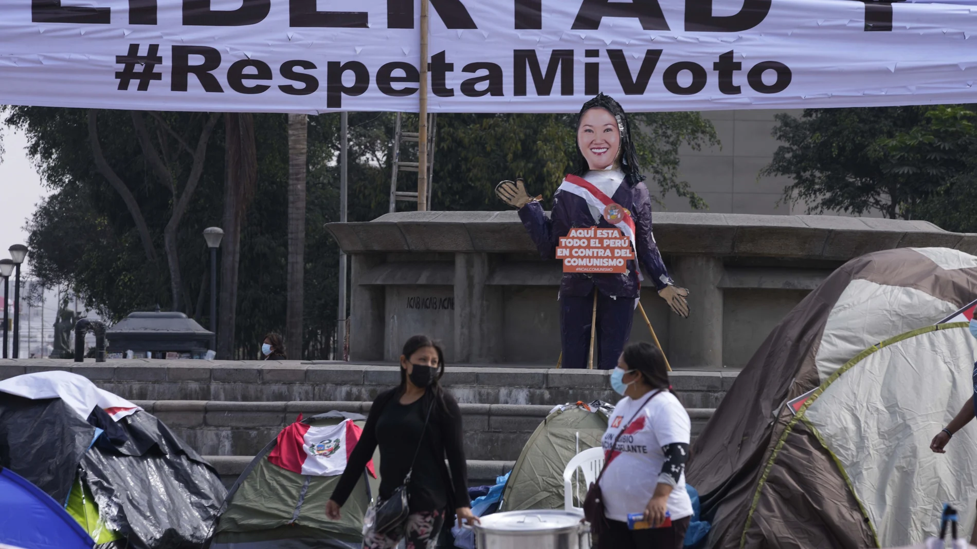 Supporters of presidential candidate Keiko Fujimori carry a large cooking pot as they camp outside the Palace of Justice, hoping to escalate claims of electoral fraud alleged by Fujimori's campaign one month after the presidential runoff election in Lima, Peru, Monday, July 12, 2021. Supporters of both presidential candidates continue to wait for an official winner of the June 6 election. The sign reads in Spanish "Freedom. Respect my vote." (AP Photo/Martin Mejia)