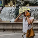 Una mujer se tapa la cabeza con un abanico para guarecerse de las altas temperaturas