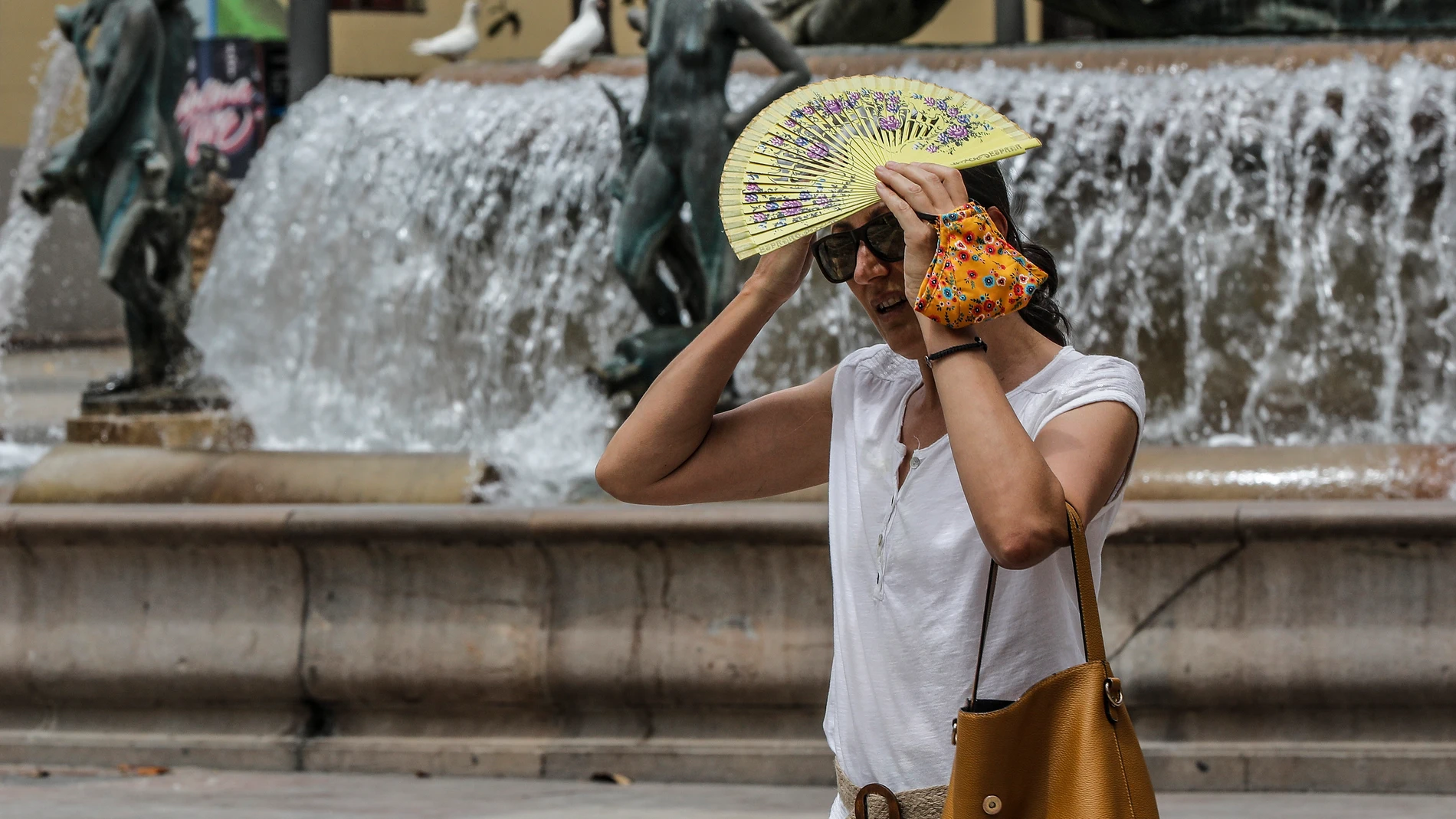 Una mujer se tapa la cabeza con un abanico para guarecerse de las altas temperaturas