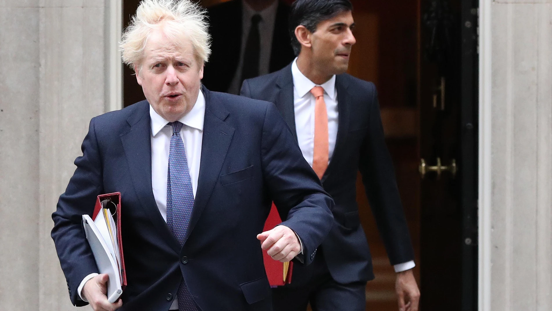 El "premier" británico, Boris Johnson, flanqueado por su ministro de Finanzas, Rishi Sunak, abandonan Dowining street