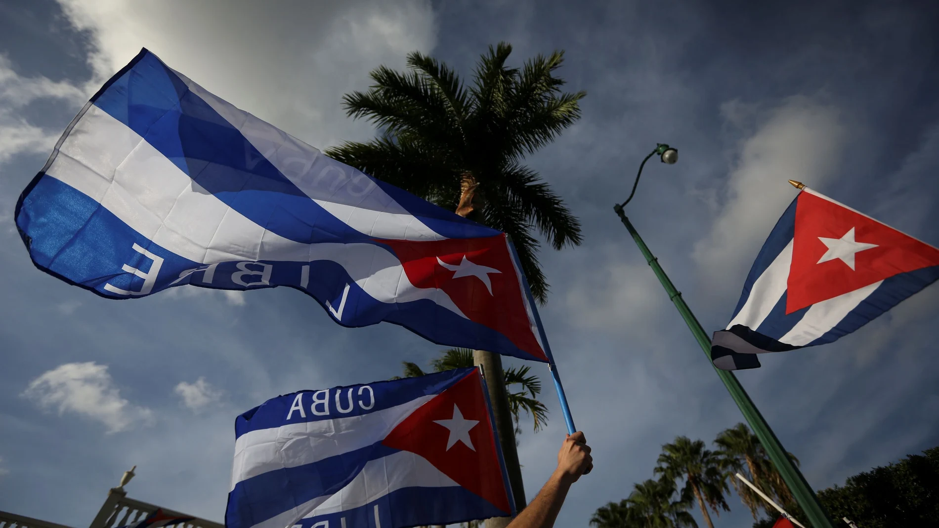 Migrantes cubanos ondean la bandera cubana en el mítico café Versailles, en Miami