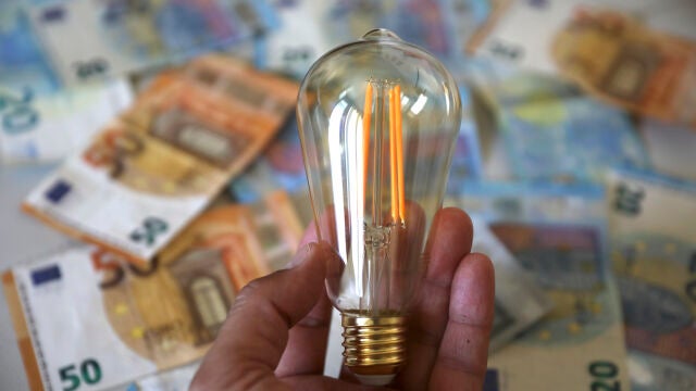 Bombilla encendida sobre dinero en efectivo