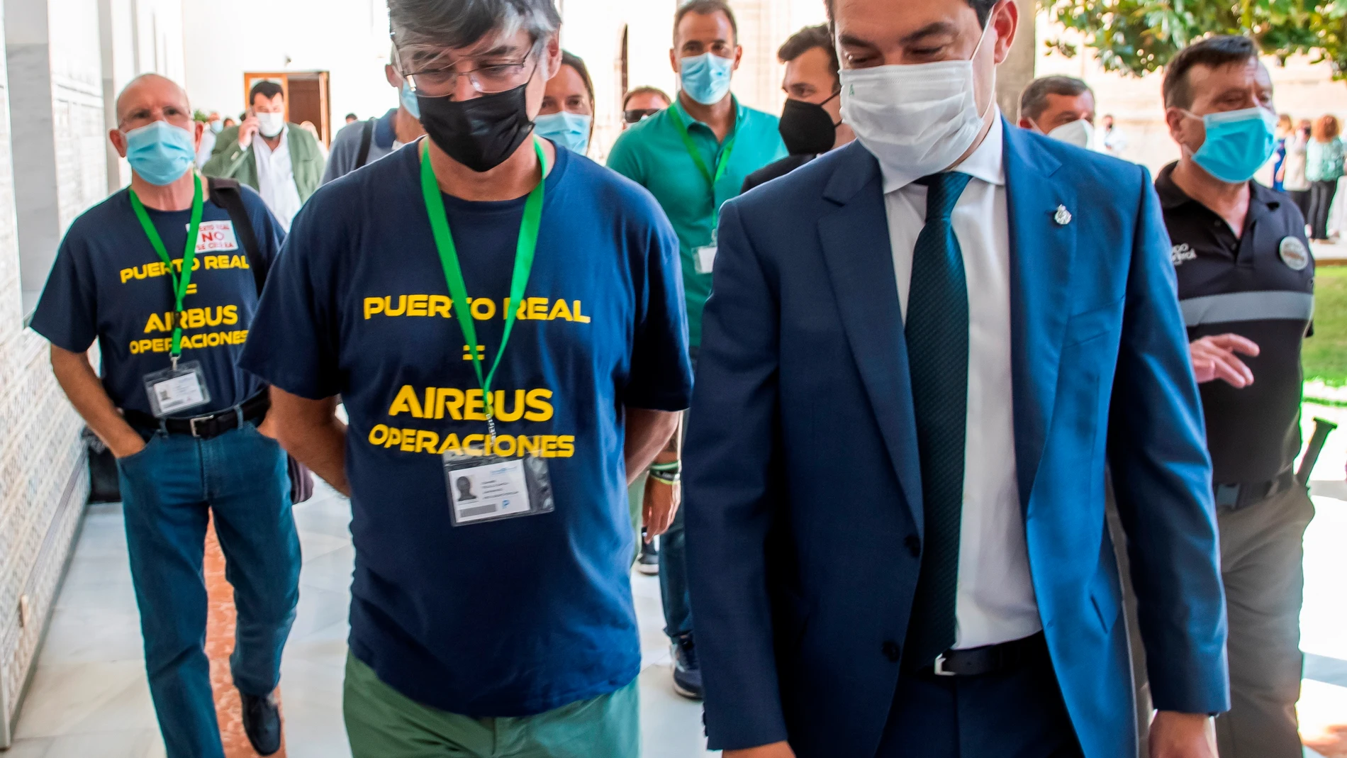 El presidente andaluz, Juanma Moreno, y representantes de los trabajadores de la planta de Airbus de Puerto Real , poco antes de la reunión informal mantenida hoy tras la sesión de control al ejecutivo