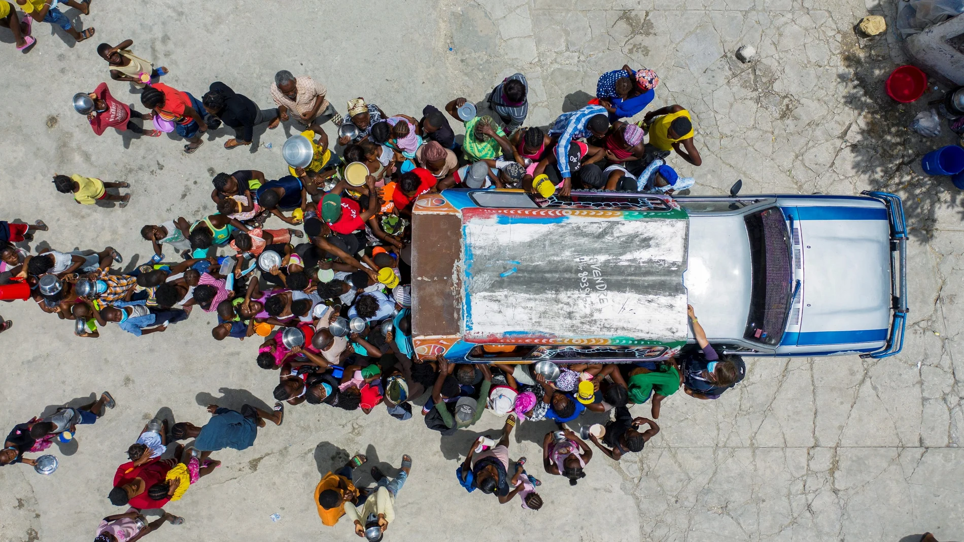 People gather around a car where volunteers distribute food to refugees at a shelter for families displaced by gang violence at the Saint Yves Church in Port-au-Prince, Haiti July 26, 2021. REUTERS/Ricardo Arduengo TPX IMAGES OF THE DAY