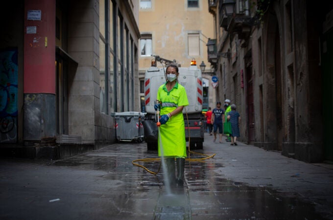 Una trabajadora limpia una vía de Barcelona
