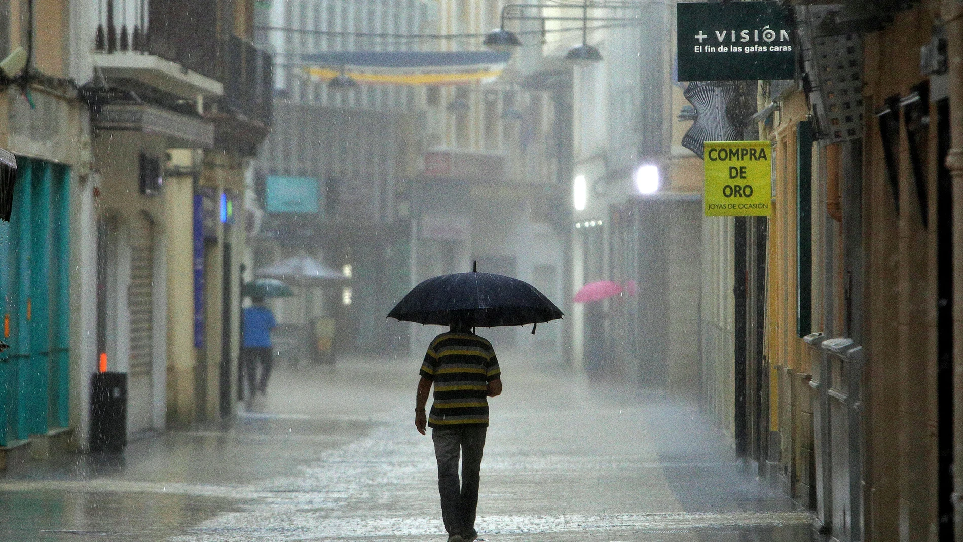 Un hombre camina bajo una intensa lluvia por el centro de la ciudad
