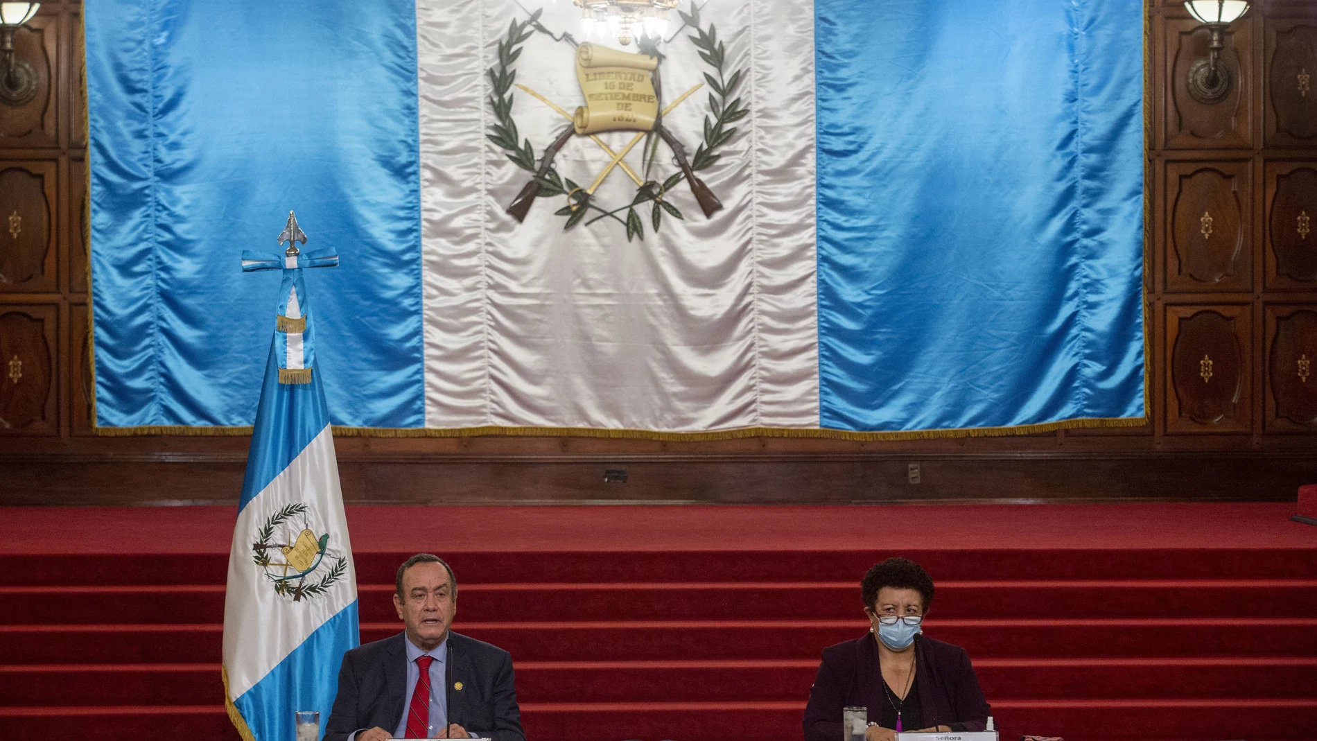 Guatemalan President Alejandro Giammattei, left, accompanied by Health minister Amelia Flores, speaks during a press conference at the National Palace in Guatemala City, Tuesday, July 27, 2021. The U.S. government has suspended cooperation with Guatemala's Attorney General's Office in response to the firing of its top anti-corruption prosecutor Juan Francisco Sandoval according to U.S. State Department. (AP Photo/Oliver de Ros)