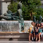 Un grupo de turistas se hace una fotografía junto a la fuente en la plaza de la Virgen de Valencia.