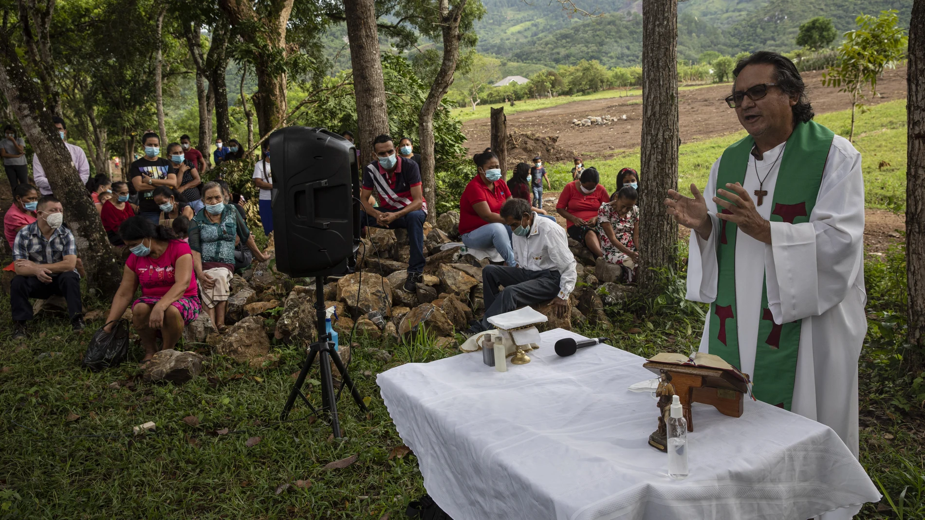 Friar Leopoldo Serrano celebrates an outdoor Mass at Mission San Francisco de Asis, in Honduras, Sunday, June 27, 2021. The pastor of souls has turned into a project manager and construction foreman for the families of La Reina, a nearby Honduran village buried in an epic mudslide in November 2020, its families among nearly half a million Central Americans displaced by Hurricanes Eta and Iota. (AP Photo/Rodrigo Abd)